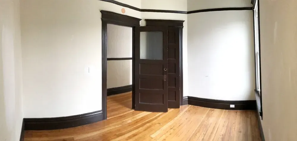A room with freshly painted white walls and dark brown wooden trim, showcasing the expert drywall and painting work by Baltodano's Drywall and Painting in Oakley.